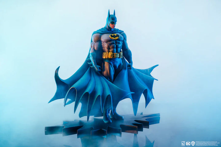 Full-body Batman statue with cape spread wide on a rocky Gotham base on a white background
