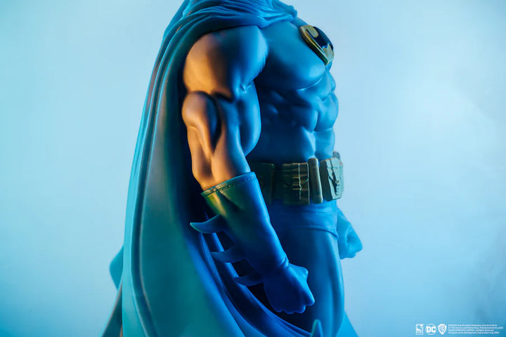 Side profile of Batman statue showing muscular arm and sculpted suit details on a white background