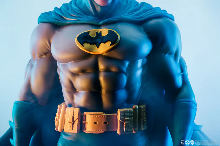 Close-up of Batman’s chest with yellow bat emblem and utility belt on a white background
